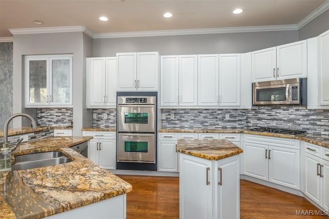 kitchen with white cabinets, sink, a kitchen island, light stone counters, and stainless steel appliances