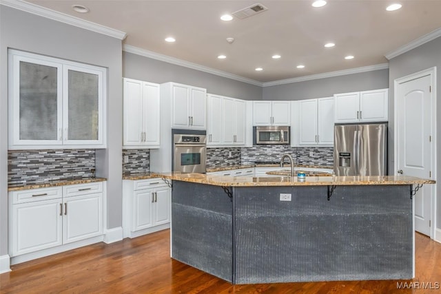 kitchen with white cabinets, dark hardwood / wood-style flooring, stainless steel appliances, and a center island with sink