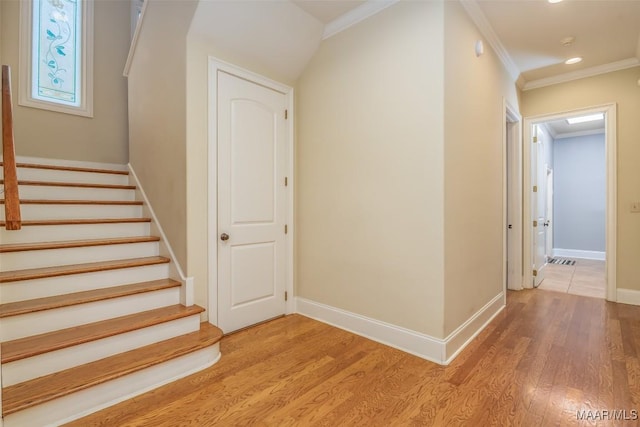 staircase with wood-type flooring and crown molding