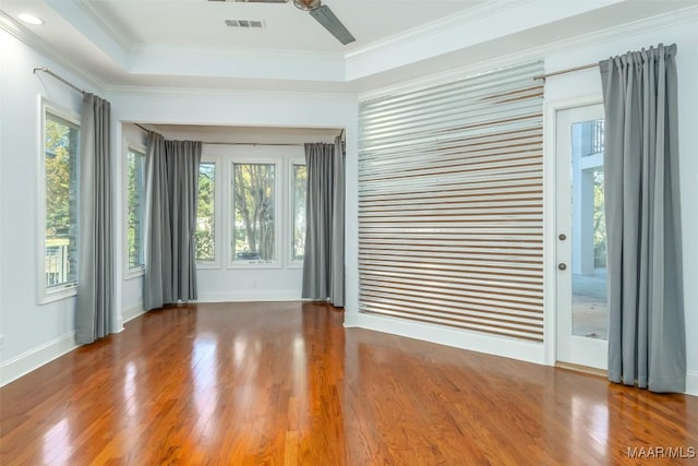 spare room featuring dark hardwood / wood-style floors, crown molding, and a wealth of natural light