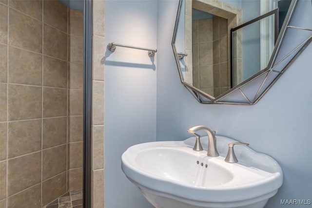 bathroom featuring a tile shower and sink