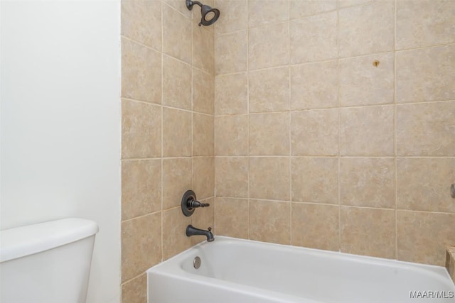 bathroom with toilet and tiled shower / bath