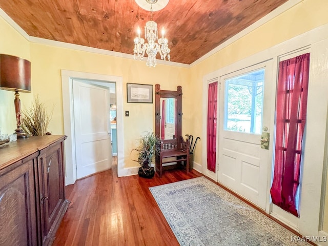 foyer entrance with wood ceiling, dark hardwood / wood-style flooring, a chandelier, and ornamental molding