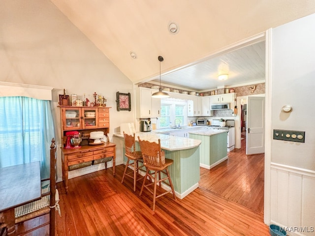 kitchen with white range with gas cooktop, light wood-type flooring, kitchen peninsula, lofted ceiling, and white cabinets