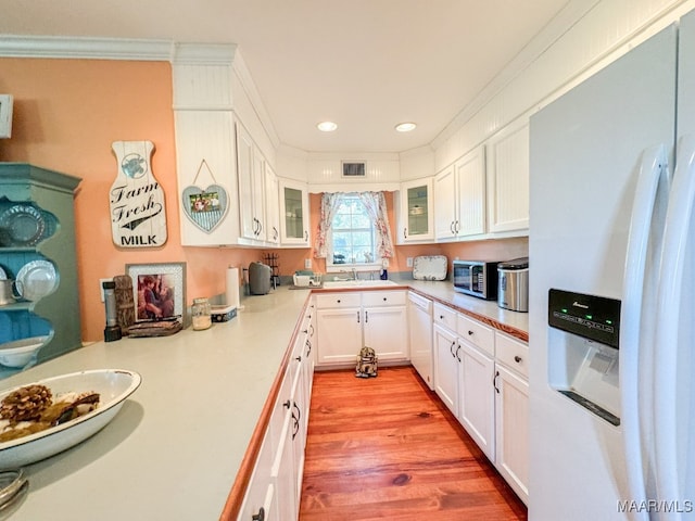 kitchen with sink, white appliances, white cabinetry, and light hardwood / wood-style floors