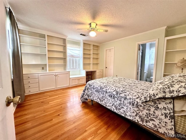 bedroom with a textured ceiling, visible vents, ornamental molding, built in study area, and light wood finished floors