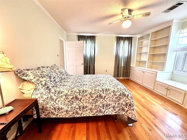 bedroom with a textured ceiling, visible vents, a ceiling fan, ornamental molding, and light wood finished floors