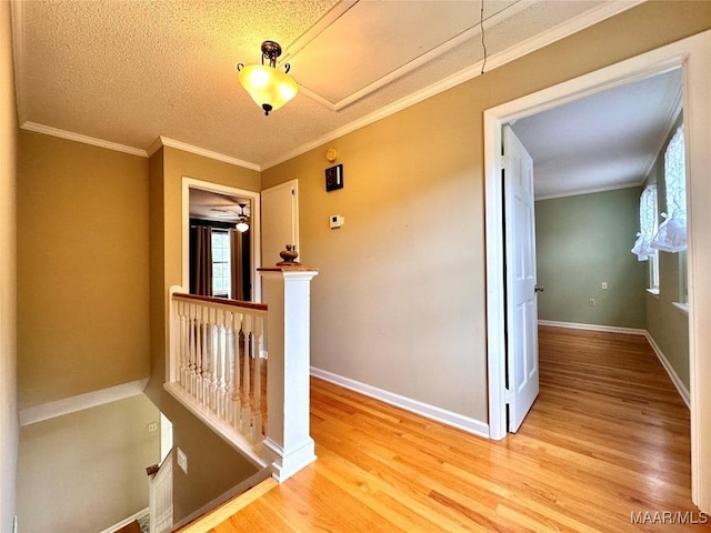 corridor with ornamental molding, light wood-type flooring, and an upstairs landing