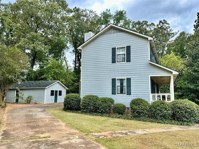 view of side of home featuring a yard, an outdoor structure, and a chimney