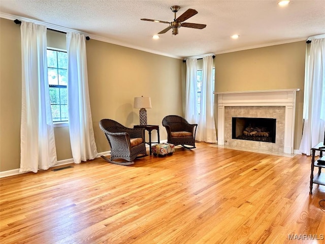 sitting room featuring visible vents, a tile fireplace, ornamental molding, wood finished floors, and a textured ceiling