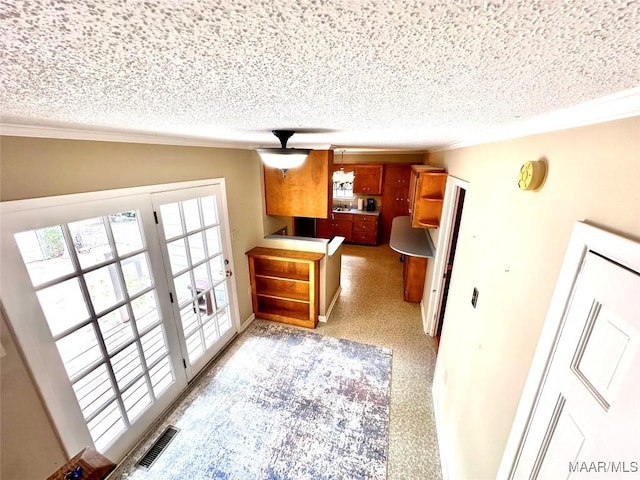 kitchen featuring visible vents, crown molding, and a textured ceiling