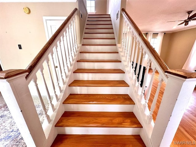 stairs featuring a textured ceiling, visible vents, wood finished floors, and a ceiling fan