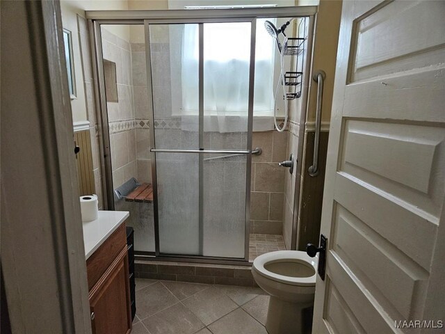 bathroom with vanity, toilet, a shower with shower door, and tile patterned flooring