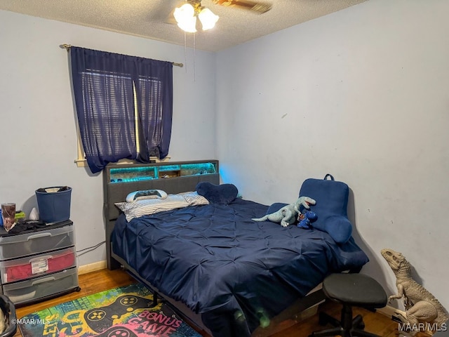 bedroom featuring a textured ceiling, ceiling fan, and wood-type flooring