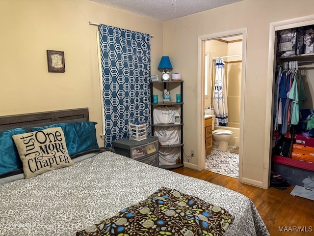 bedroom with a closet, hardwood / wood-style flooring, ensuite bathroom, and a textured ceiling