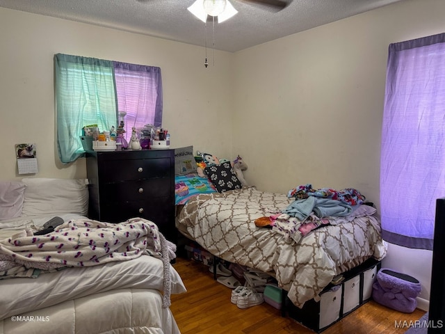 bedroom with a textured ceiling, hardwood / wood-style floors, and ceiling fan