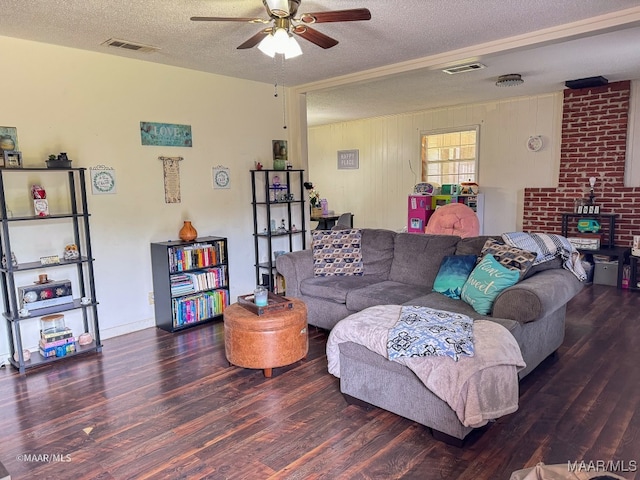 living room with dark hardwood / wood-style flooring, wooden walls, ceiling fan, and a textured ceiling