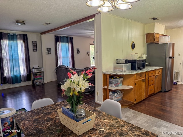 kitchen featuring dark wood-type flooring, a textured ceiling, a chandelier, and stainless steel refrigerator