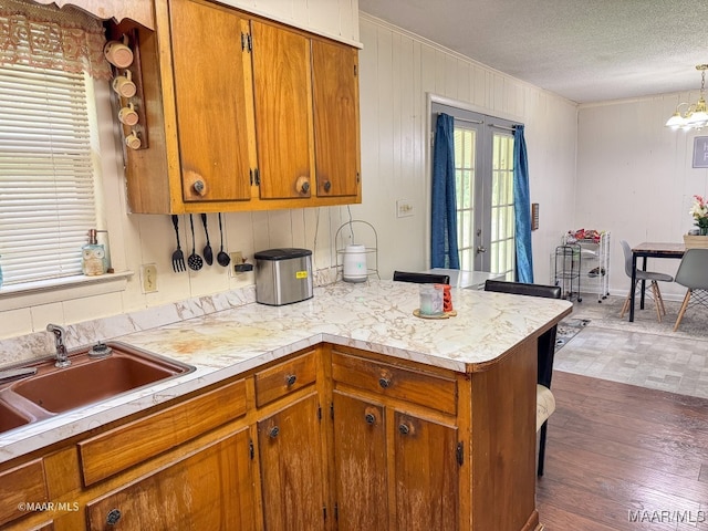 kitchen featuring hanging light fixtures, french doors, dark hardwood / wood-style flooring, sink, and a textured ceiling