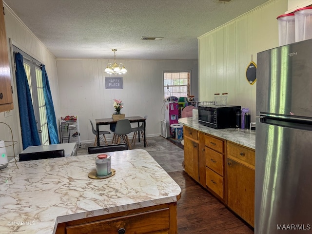 kitchen with stainless steel fridge, dark hardwood / wood-style flooring, a notable chandelier, ornamental molding, and wooden walls