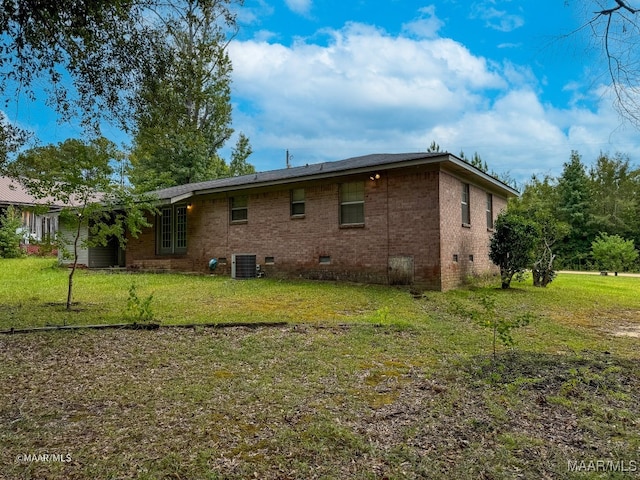 rear view of property with central AC unit and a lawn