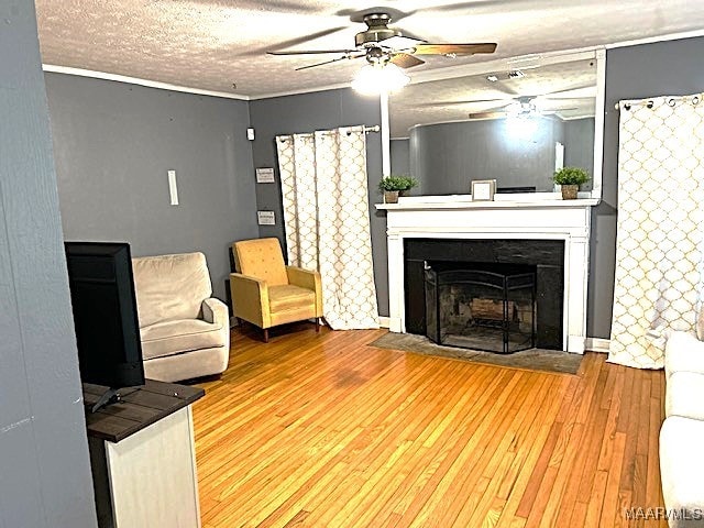 living room with ceiling fan, wood-type flooring, and a textured ceiling