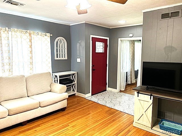 living room featuring ornamental molding, a textured ceiling, hardwood / wood-style floors, and ceiling fan