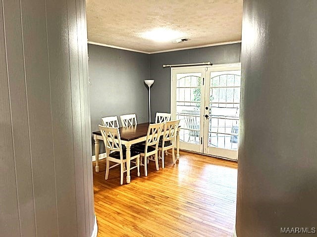 dining area with light hardwood / wood-style floors, a textured ceiling, and french doors