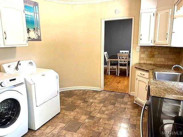 laundry area featuring dark wood-type flooring, cabinets, washing machine and dryer, and sink