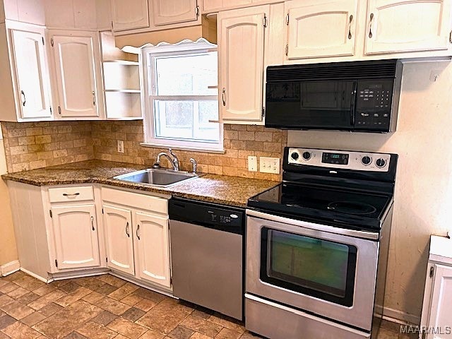 kitchen with dark stone countertops, appliances with stainless steel finishes, backsplash, and sink