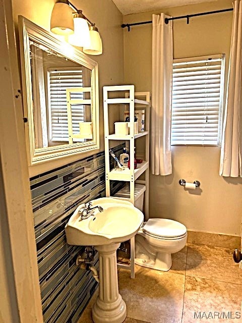 bathroom with toilet, tile patterned floors, and tasteful backsplash