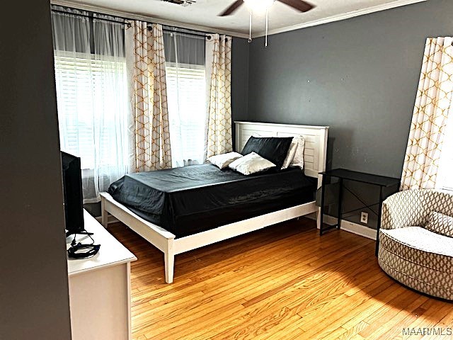 bedroom featuring ceiling fan, ornamental molding, and light wood-type flooring