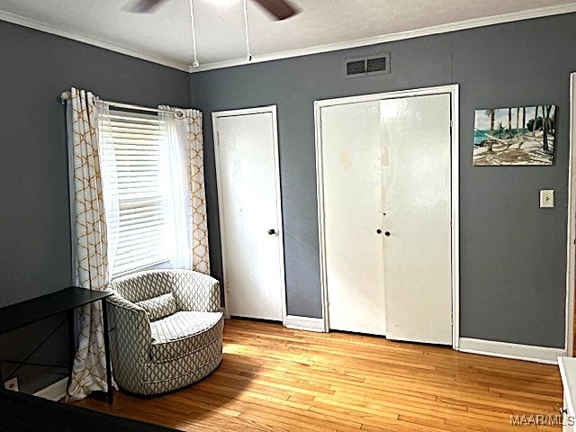 living area featuring ceiling fan, ornamental molding, and light wood-type flooring