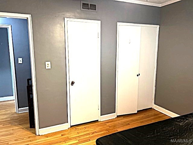 unfurnished bedroom featuring crown molding and light hardwood / wood-style floors