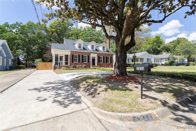 cape cod home with brick siding and fence