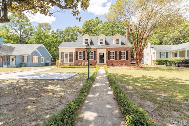 cape cod house featuring a front yard and brick siding