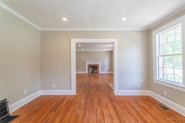 spare room with a textured ceiling, crown molding, and hardwood / wood-style flooring