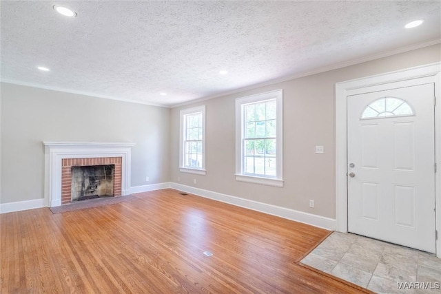 2056 Gorgas St, Montgomery, AL 36106 - foyer entrance featuring light wood-style flooring, a textured ceiling, a fireplace, crown molding, and baseboards