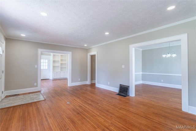 unfurnished room with a textured ceiling, crown molding, an inviting chandelier, and hardwood / wood-style flooring