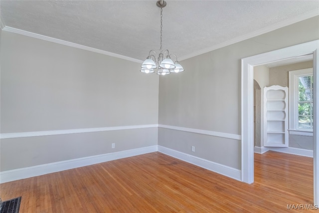 spare room featuring ornamental molding, a textured ceiling, a chandelier, and hardwood / wood-style floors