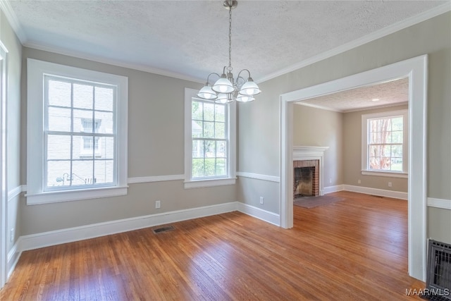 unfurnished living room with wood-type flooring, a fireplace, a notable chandelier, and plenty of natural light