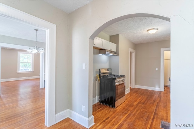 corridor with a textured ceiling, a notable chandelier, and hardwood / wood-style flooring