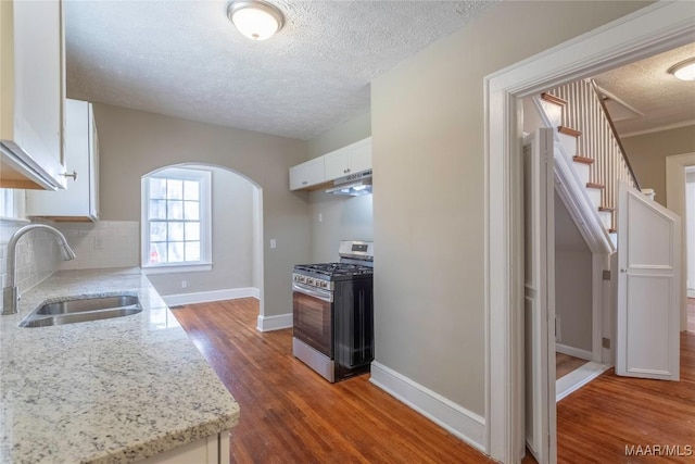 2056 Gorgas St, Montgomery, AL 36106 - kitchen featuring a sink, backsplash, white cabinetry, gas stove, and arched walkways