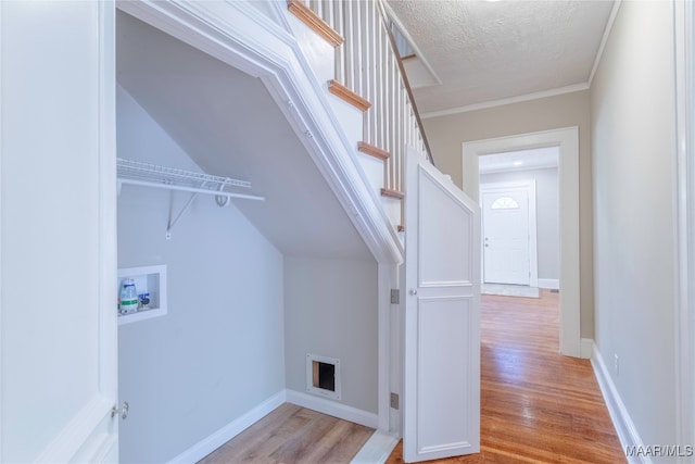 laundry room with washer hookup, hardwood / wood-style flooring, crown molding, and a textured ceiling