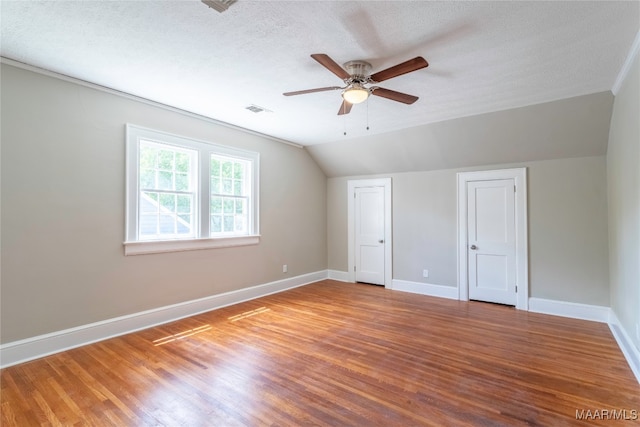 interior space featuring a textured ceiling, ceiling fan, vaulted ceiling, and light hardwood / wood-style floors