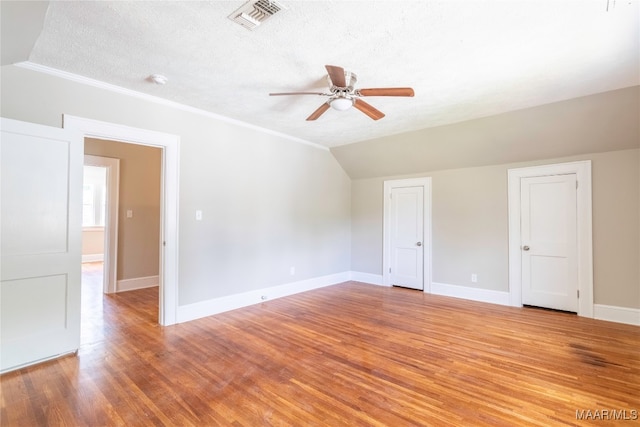 interior space with lofted ceiling, ceiling fan, light wood-type flooring, and a textured ceiling