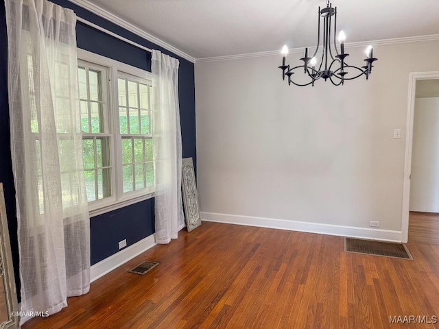 empty room featuring visible vents, crown molding, baseboards, and wood finished floors