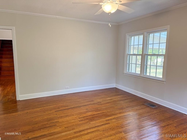 spare room with visible vents, baseboards, wood finished floors, and crown molding