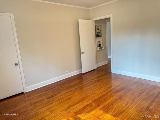 spare room with wood finished floors, baseboards, and ornamental molding