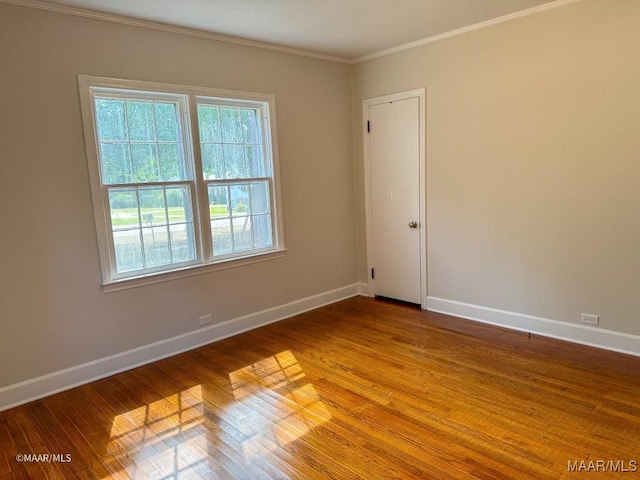 unfurnished room with crown molding, wood finished floors, and baseboards